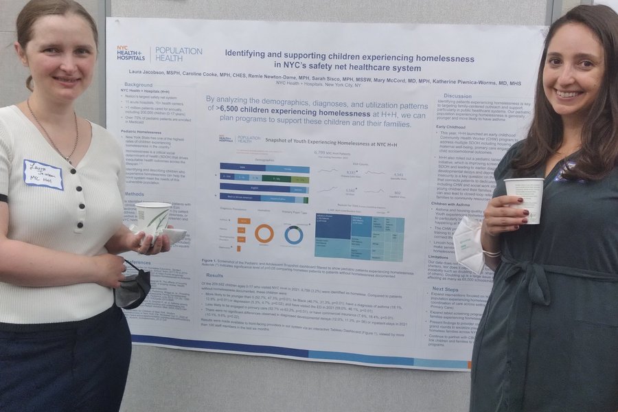 Laura Jacobson, MSPH, and Caroline Cooke, MPH, stand with their project, "Identifying and supporting children experiencing homelessness in NYC's safety net healthcare system"